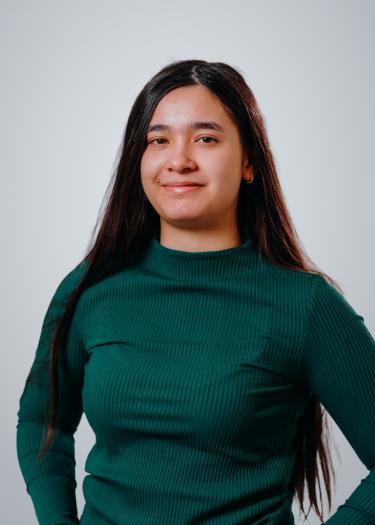 A woman with dark coloured hair in a dark green jumper, smiling